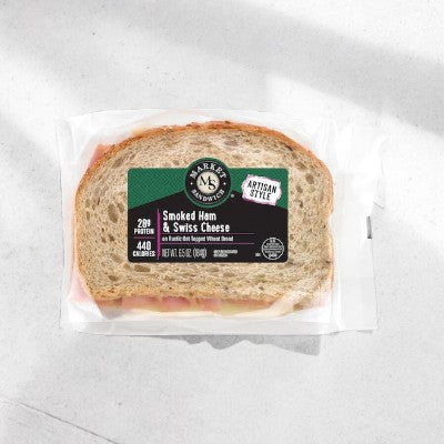 The E.A. Sween Ham & Swiss sandwich boasts premium ham and creamy Swiss cheese on oat-topped wheat bread, with branding and nutritional info, all set against a white backdrop. Ships frozen; has a 30-day shelf life once refrigerated.