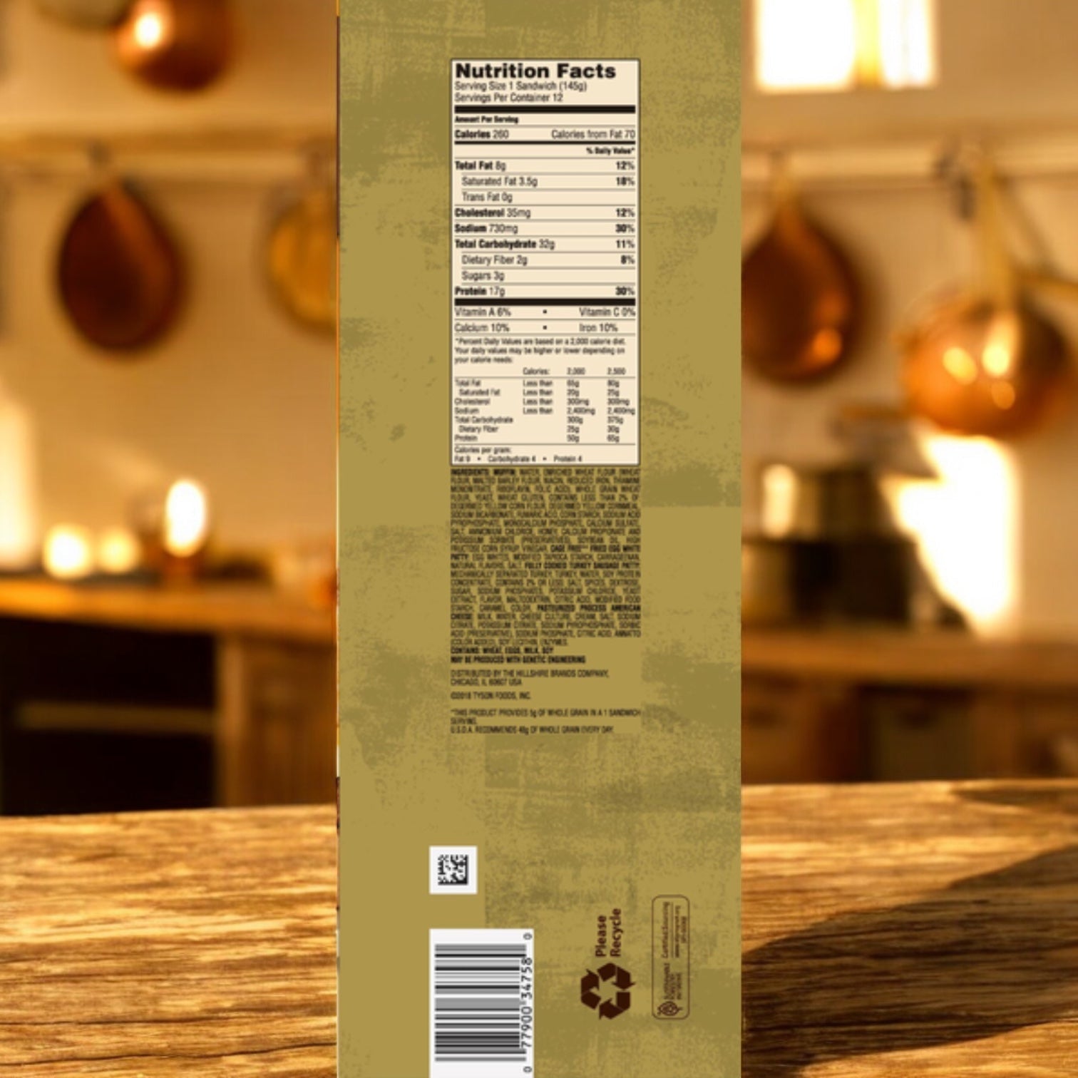 A Jimmy Dean Delights English Muffin 12 Pack, 1 Count, features an English muffin sandwich with nutrition facts and recycling symbols. It rests on a wooden surface in a kitchen with hanging pots, highlighting a wholesome breakfast option.