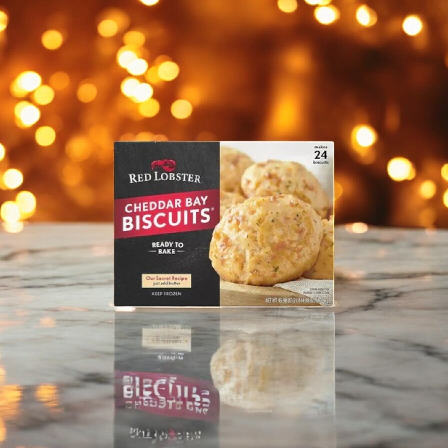 A box of Aqua Star King Crabs & Cheddar Bay Biscuits Combo by Easy Lunches sits on a marble surface, suggesting the allure of a Seafood Feast, with warm, blurred lights in the background.