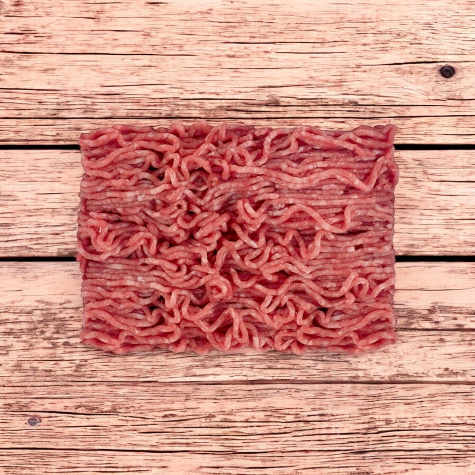 A vacuum-packed block of Patuxent Farms Halal Ground Lamb 80/20 (raw, frozen) sits neatly on a light wooden surface, showing visible strands of meat. Comes in 5 packs of 2 lbs each (10 lbs total).