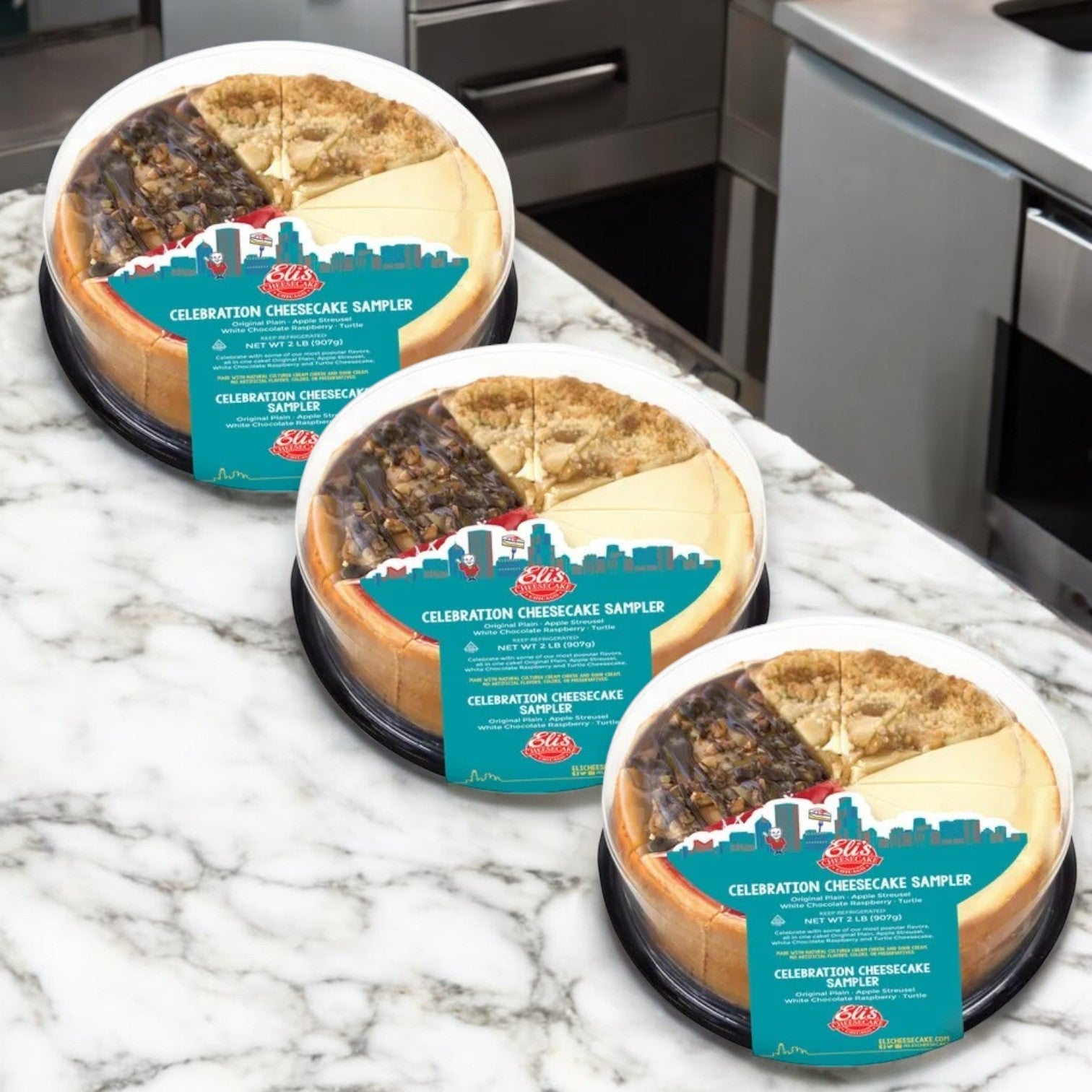 Three packs of Eli's Cheesecake Celebration Sampler, 32 oz. each, are elegantly displayed on a marble countertop in a cozy kitchen setting.
