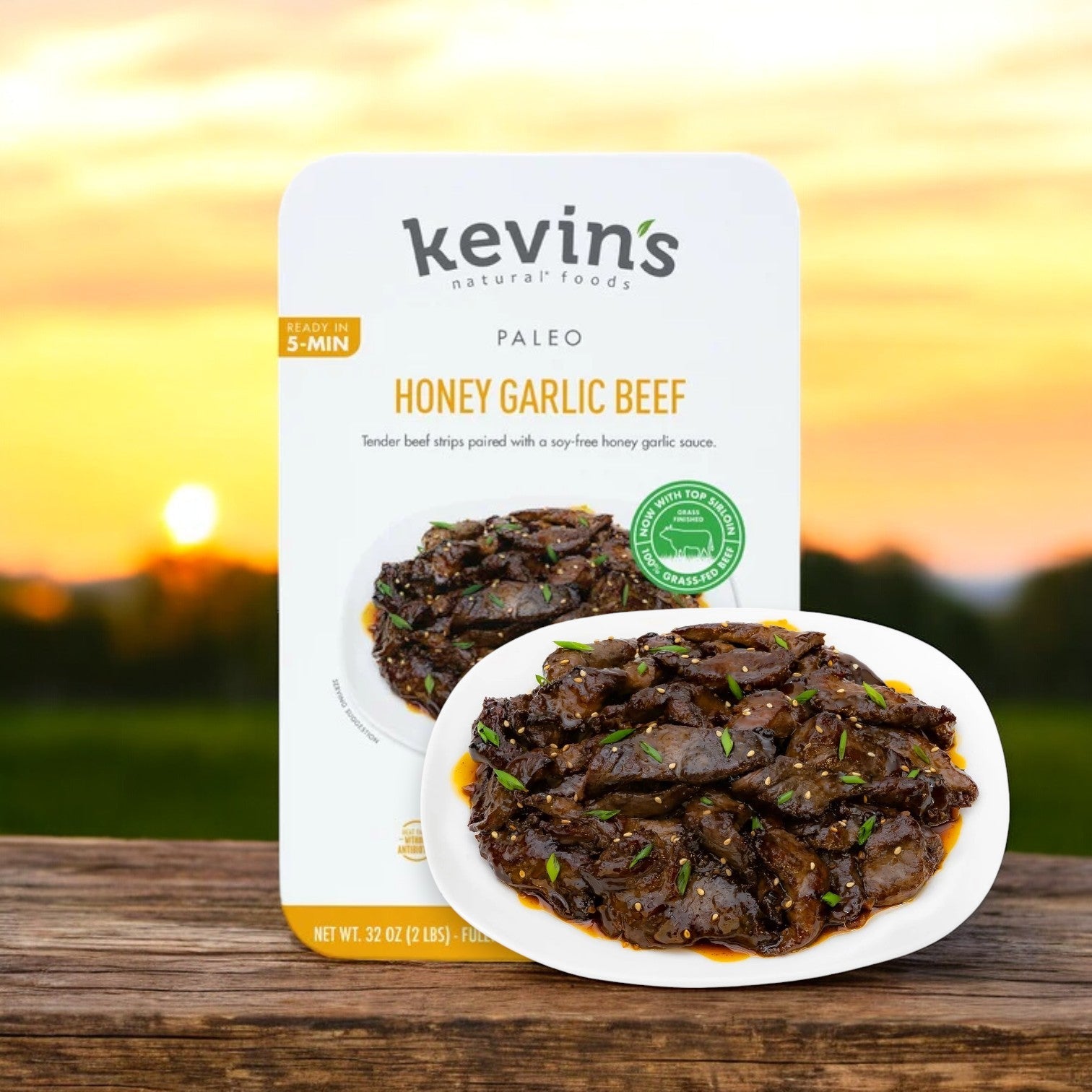 Kevin's Honey Garlic Beef, 32 oz., 1 case (4 packs), with all-natural and gluten-free ingredients, is served elegantly on a white plate against a sunset backdrop. Ships frozen; lasts 30 days in cooler after removal from freezer.