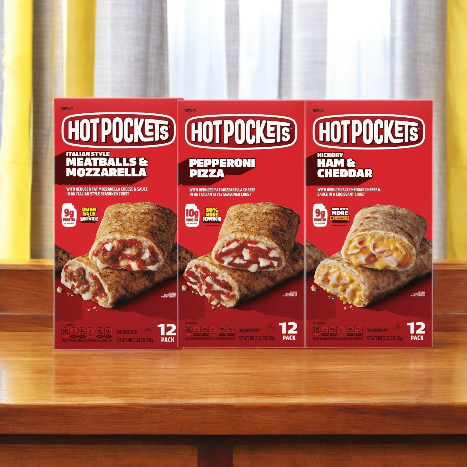 A 3-pack Hot Pockets Variety Pack! with 36 total pockets rests on a wooden surface, offering a tempting trio of flavors: Meatballs & Mozzarella, Pepperoni Pizza, and Ham & Cheddar. These frozen treats provide a tasty, convenient meal for any time of day.