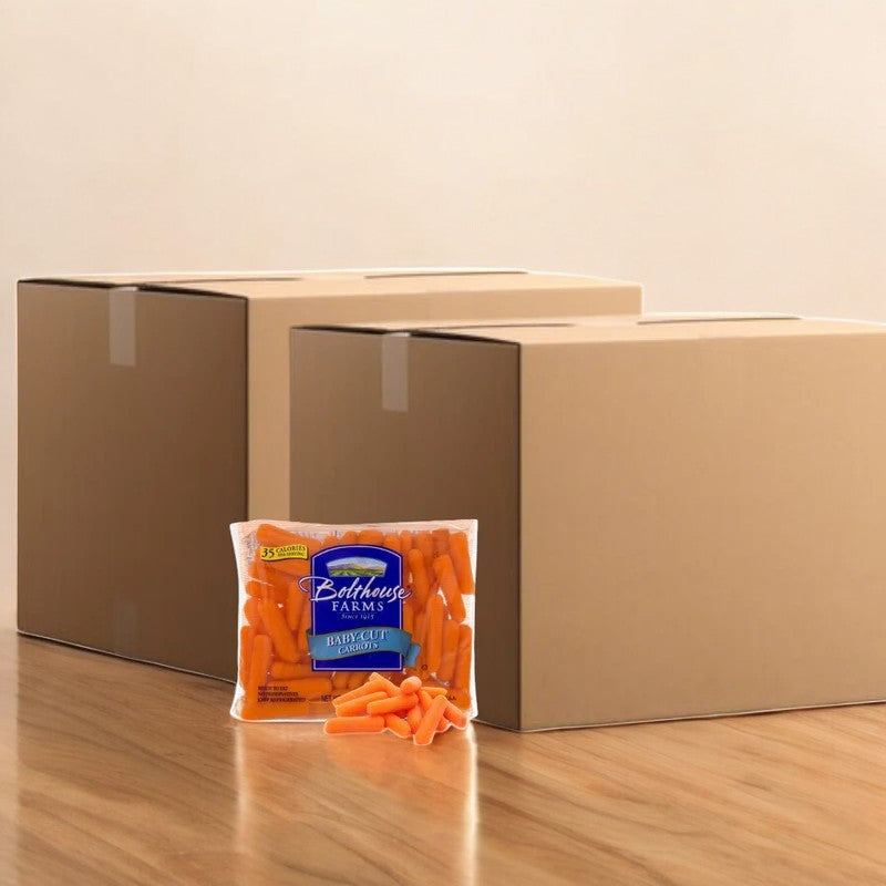 A bag of Bolthouse Farms Carrots Baby Cut Peeled, 1.6 oz.- 400 Count, a healthy snack rich in dietary fiber, is placed in front of two large cardboard boxes on a wooden floor.