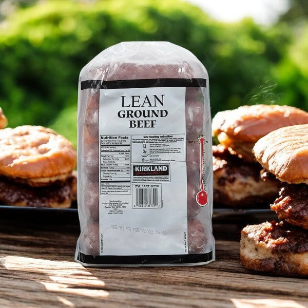 A pack of Kirkland Signature Lean Ground Beef-5 Pounds sits on the table, surrounded by freshly cooked burgers amidst lush greenery. Ideal for your next meal prepping session.