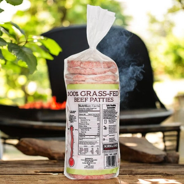 A Kirkland Signature Grass-Fed Beef Patties pack, featuring 15 antibiotic-free patties, rests by the barbecue grill with nutritional info and cooking instructions on the label.