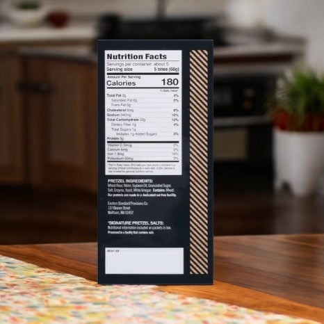 In the kitchen, a nutrition facts label for Eastern Standard Provisions Pretzel Bites - 1 Count sits on a wooden counter, showcasing their premium ingredients.
