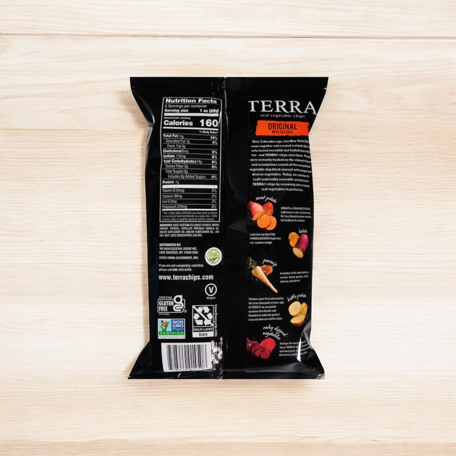 A Terra Original Chips, 5 oz., bag rests on a wooden surface featuring nutrition facts, ingredients, and vibrant root vegetable illustrations—a great choice for a healthy snack.