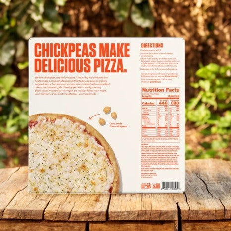 The Banza Vegan Cheese Pizza- 1 Count from Banza is displayed on a wooden table, framed by lush greenery, with nutritional information and cooking instructions clearly visible.