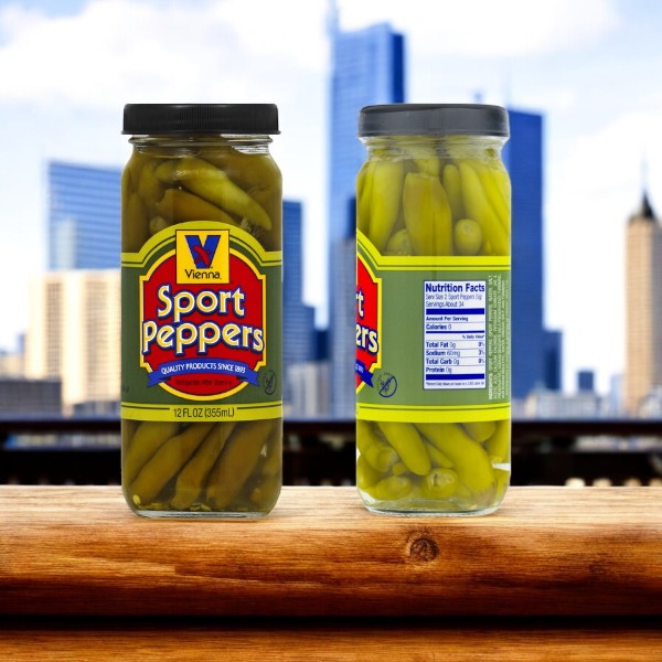 Two jars of Vienna Beef Sport Peppers sit in front of a blurred cityscape. One jar faces forward, the other shows its side and nutritional info, ideal partners for the Vienna Hot Dog Kit! Chicago Style with 32 hot dogs, condiments, and buns to complete your authentic Chicago-style experience.
