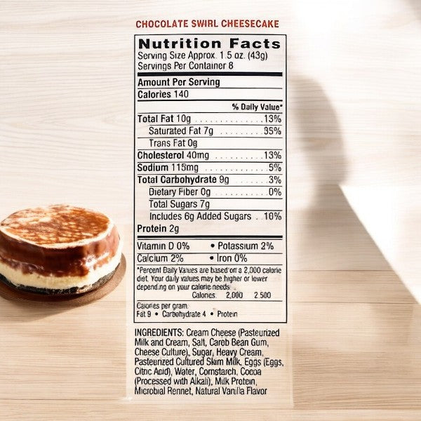 A Junior's Mini Cheesecake from the variety pack sits gracefully on the wooden table, evoking the classic taste of Junior's Restaurant, accompanied by a label displaying its nutritional facts and ingredients.