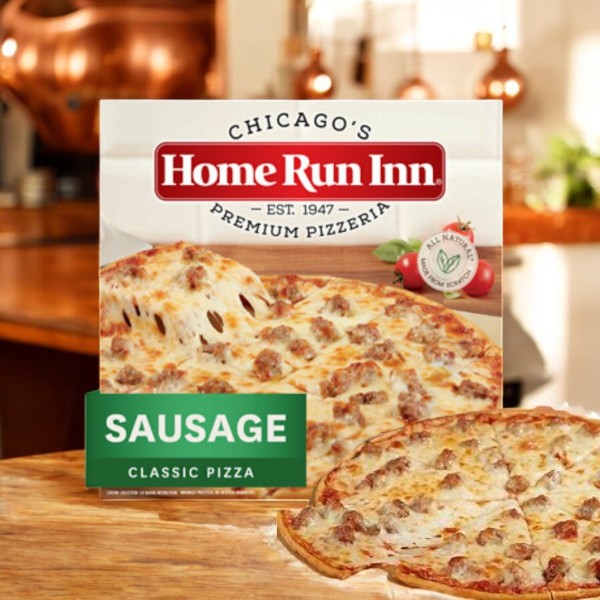 A box of Home Run Inn Family Size Classic Frozen Sausage Pizza, 30 oz., is on the kitchen counter with the freshly baked pizza in front.