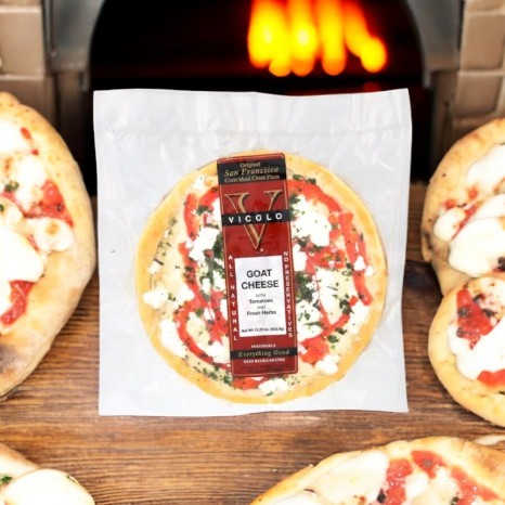 A Vicolo Goat Cheese Pizza sits temptingly in front of a wood-fired oven, nestled among an array of gourmet pizzas.