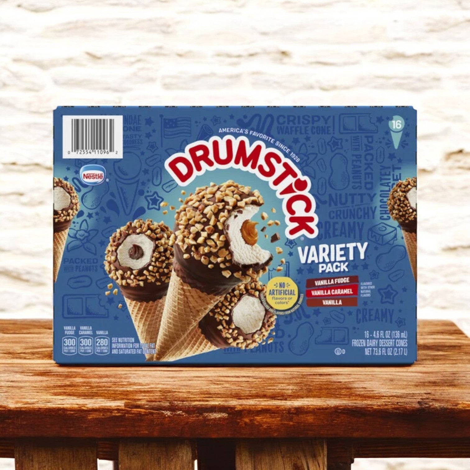 Nestle Drumstick Cone Variety Pack, Frozen 16 ct. - 3 Boxes by Nestle is shown on a wooden surface against a brick wall, with images of the cones and nutrition info visible on the packaging.