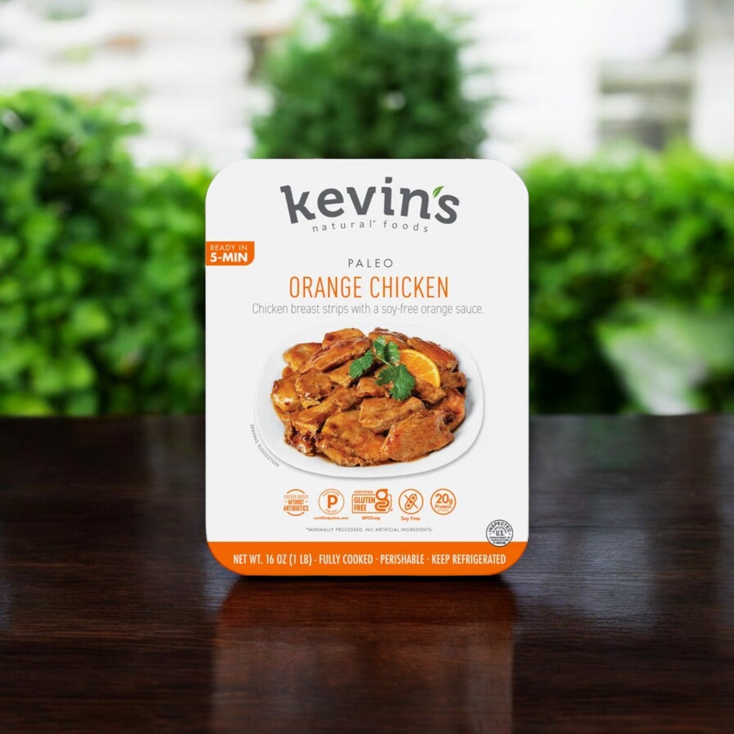 Kevin's packaging highlights their Natural Foods Orange Chicken, 16 oz. - 1 Case, in a set of 5 packs. The product features soy-free, gluten-free chicken breast strips in orange sauce, displayed against a blurred outdoor background, with a shelf life of 30 days once out of the freezer.
