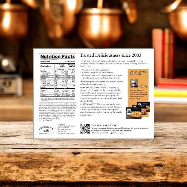 The package of Beecher's Handmade Cheese Gluten Free "World's Best" Mac & Cheese showcases nutrition facts, cooking instructions, and a glowing customer testimonial. In a cozy kitchen with copper pots and a blurred background, it promises premium comfort food.