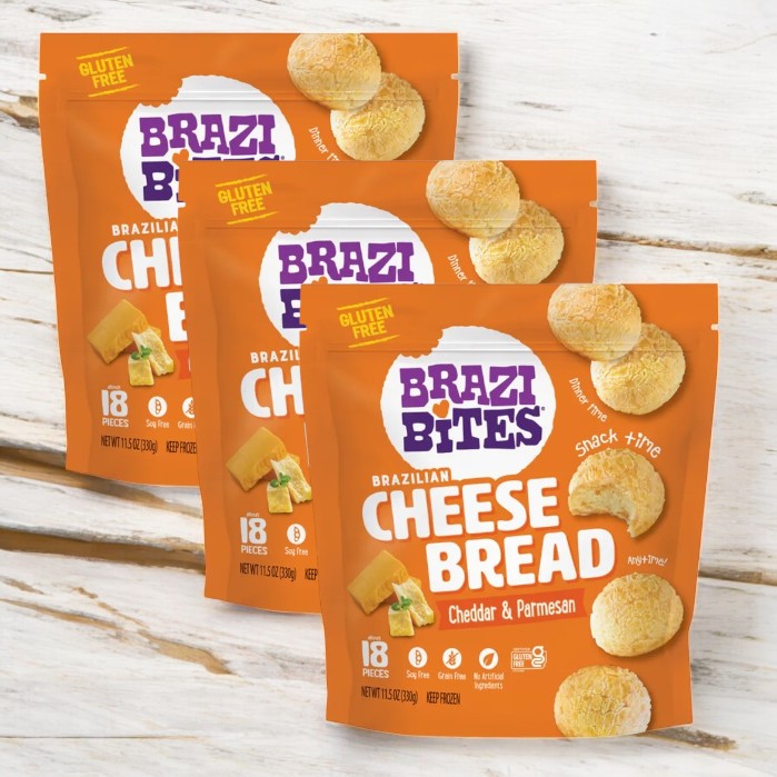 Three bags of Brazi Bites Cheddar & Parmesan Brazilian Cheese Bread (11.5 oz.) are displayed on a wooden surface.