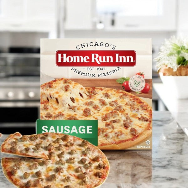 A Home Run Inn Family Sausage Pizza, 30 oz., rests invitingly on the countertop, its buttery flaky crust beckoning you closer. A slice is lifted, revealing a rich layer of mozzarella that promises a mouthwatering experience.