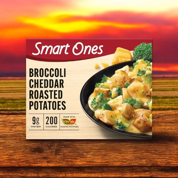 Set against a sunset, the Smart Ones Broccoli & Cheddar Roasted Potatoes Frozen Meal is a convenient and comforting choice at 200 calories with 9g of protein, perfect for microwave cooking with its delightful cheesy twist.