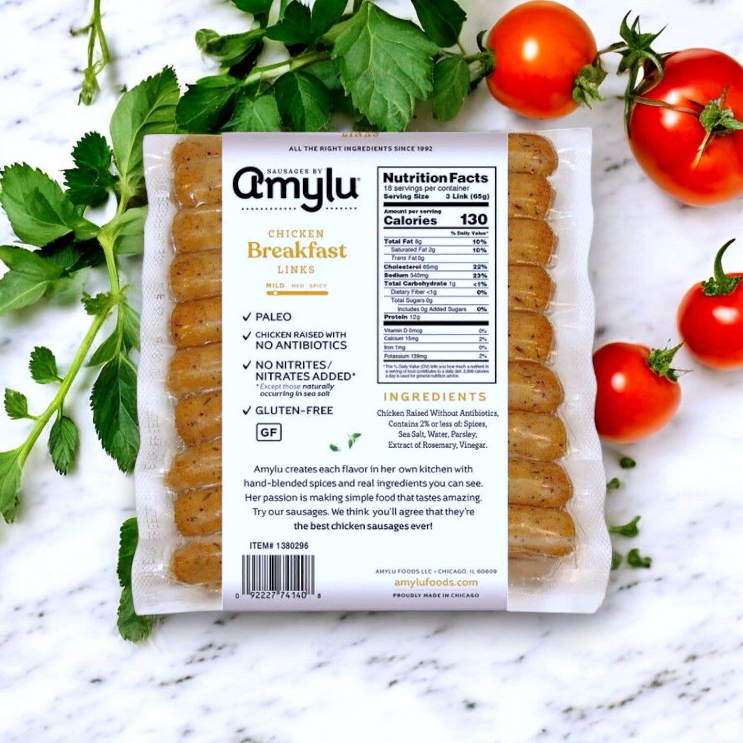 A 2.5 lbs package of Amylu Chicken Breakfast Sausage Links is set against a white background with fresh tomatoes and parsley. The packaging, labeled gluten-free, displays nutritional facts and ingredients clearly.