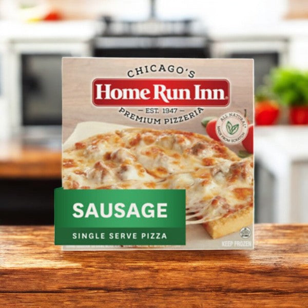 An 8.5 oz. Home Run Inn Mini Personal Pizza, Classic Frozen Sausage Pizza rests on a wooden table, offering a tasty sausage topping ideal for a quick meal, against the cozy ambience of a warm kitchen.