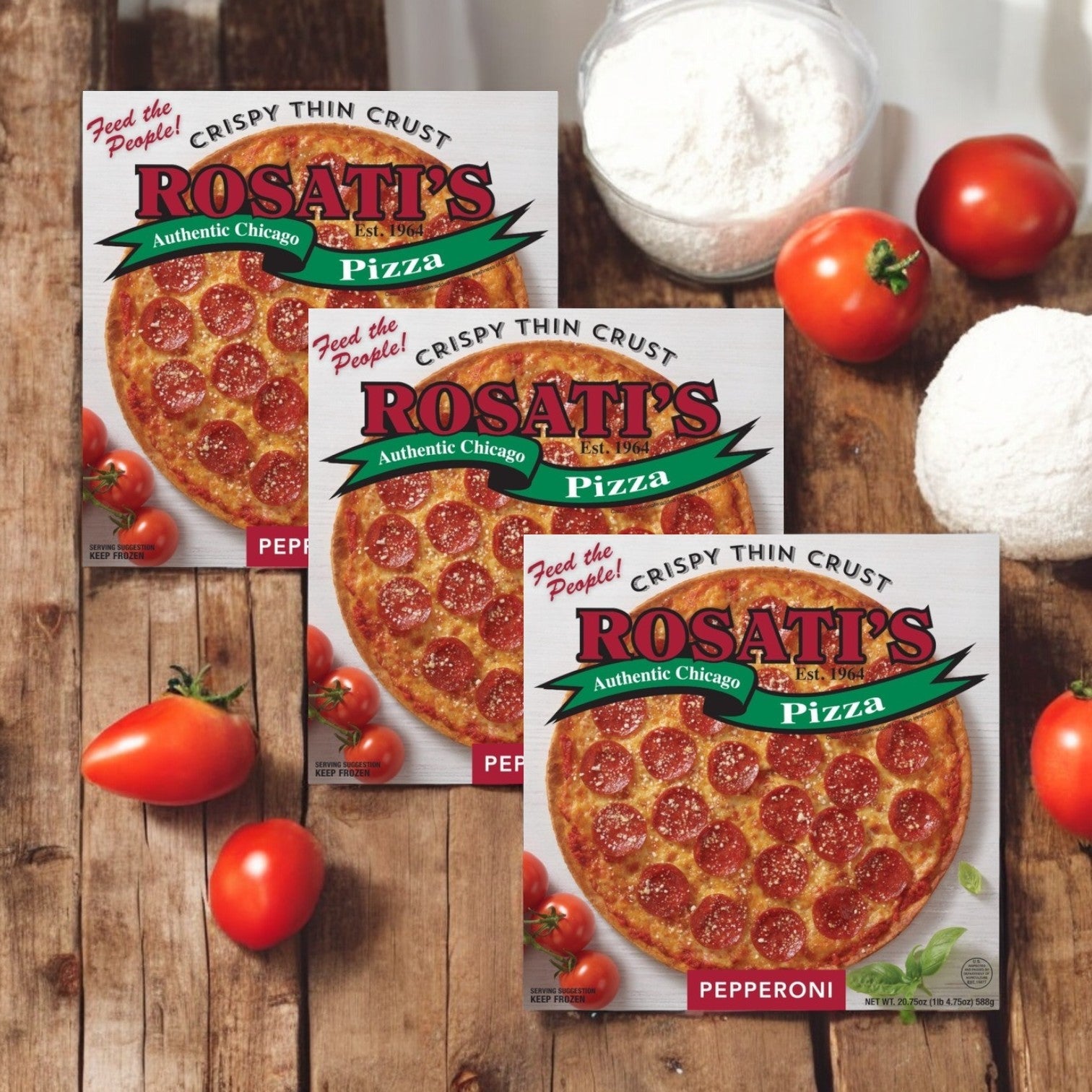 Three boxes of Rosati's Pizza Crispy Thin Crust Pepperoni (20.75 oz., 3 Count) are showcased on a wooden surface with ripe tomatoes, flour, and dough, while the aroma of melted mozzarella cheese completes the mouthwatering scene.