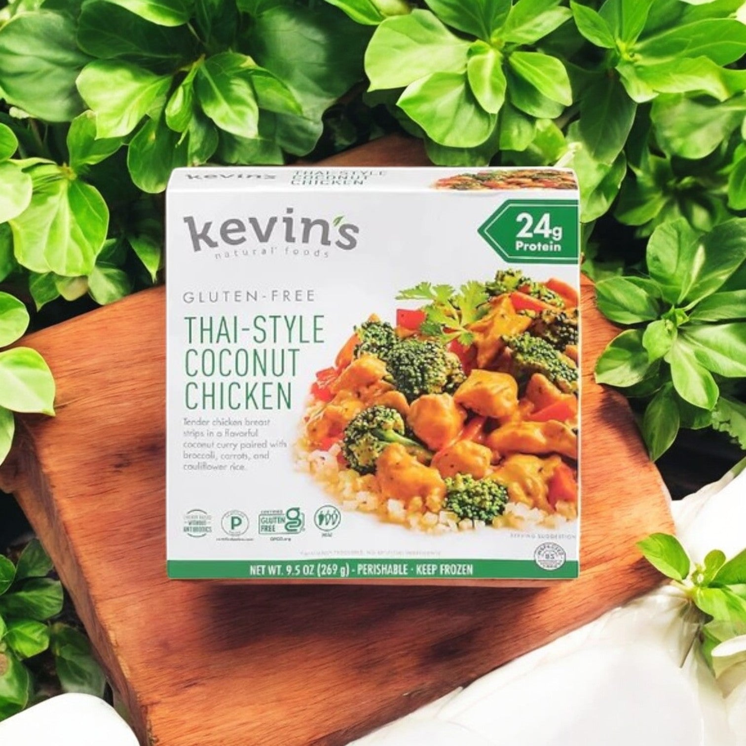 A box of Kevin's 4 Pack Combo - Gluten-Free Gourmet Meals (9.5 oz each) is positioned on a wooden surface surrounded by green leaves.