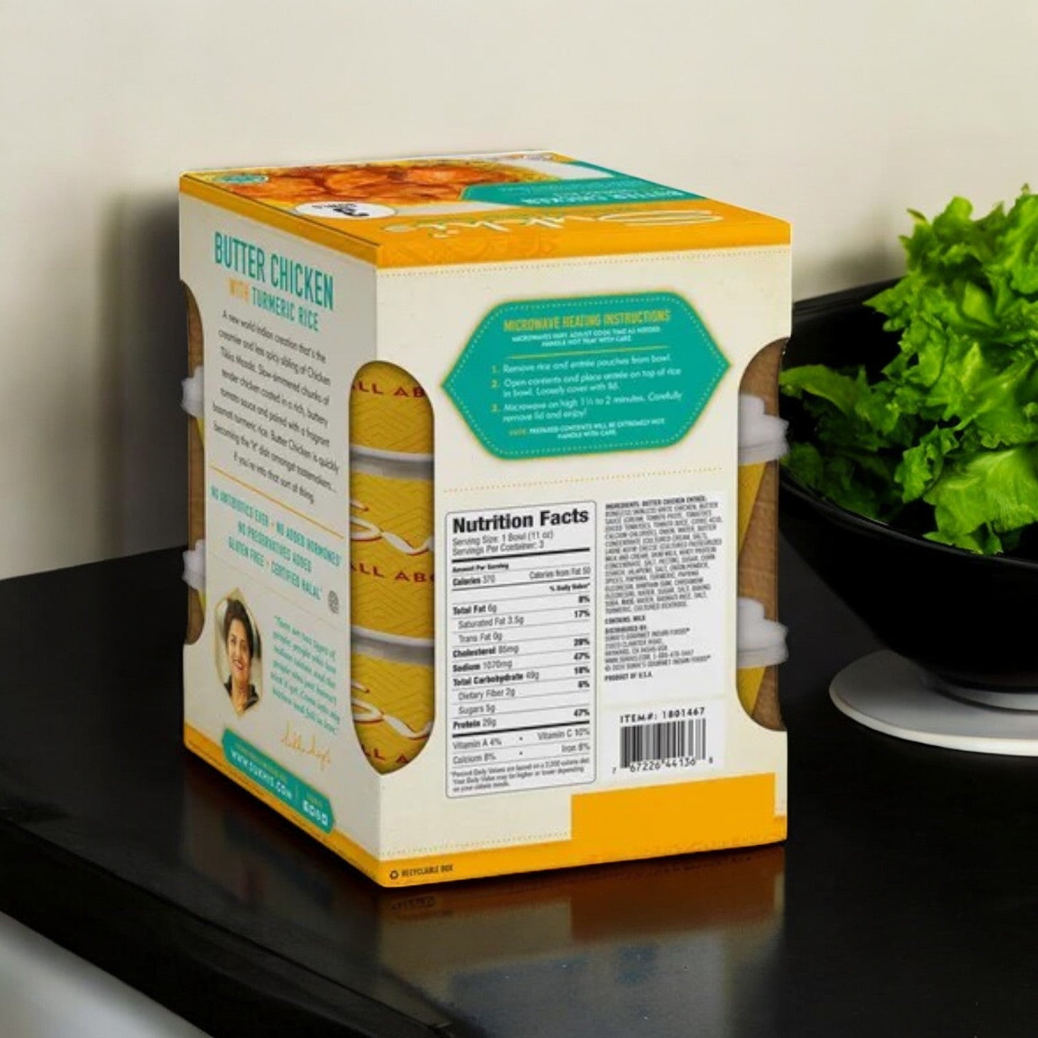 A Sukhi's Butter Chicken with Turmeric Rice from a 3-pack case rests on the counter next to green lettuce, showcasing nutritional facts that promise a delicious and balanced meal.