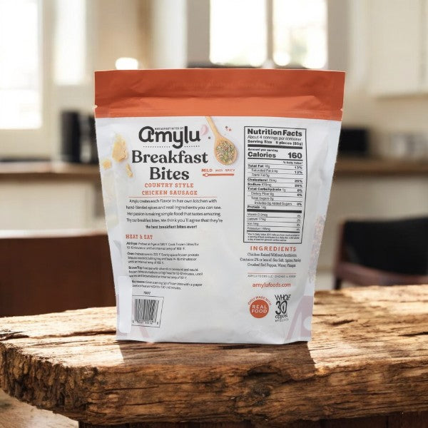 A package of Amylu Breakfast Bites, Country Style Chicken Meatballs - 3 Count, displays ingredients and nutritional facts on a wooden kitchen table. Ideal as a protein-rich snack to start your day.