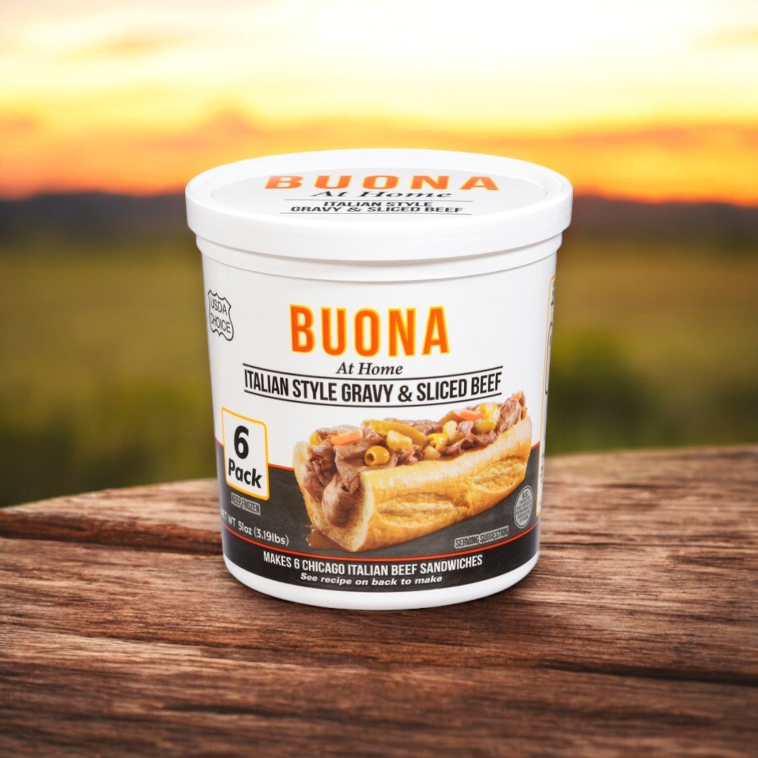 A "BUONA At Home" container displays an Italian Meal Bundle featuring Buona Gravy & Sliced Beef, Italian Style – 6 Pack, against a blurred outdoor background on a wooden surface, capturing traditional flavors.