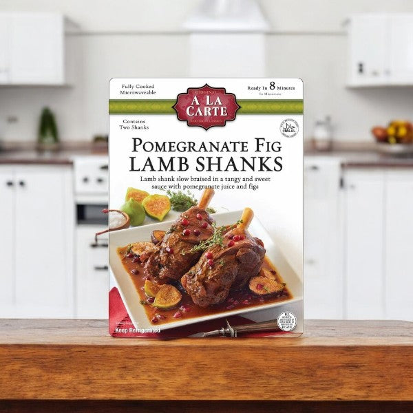 A box of A La Carte Pomegranate Fig Lamb Shanks, 2 Count-1 Pack, on the counter offers a unique culinary journey. The packaging boasts tender lamb in a rich sauce, enticing you to enjoy every bite.