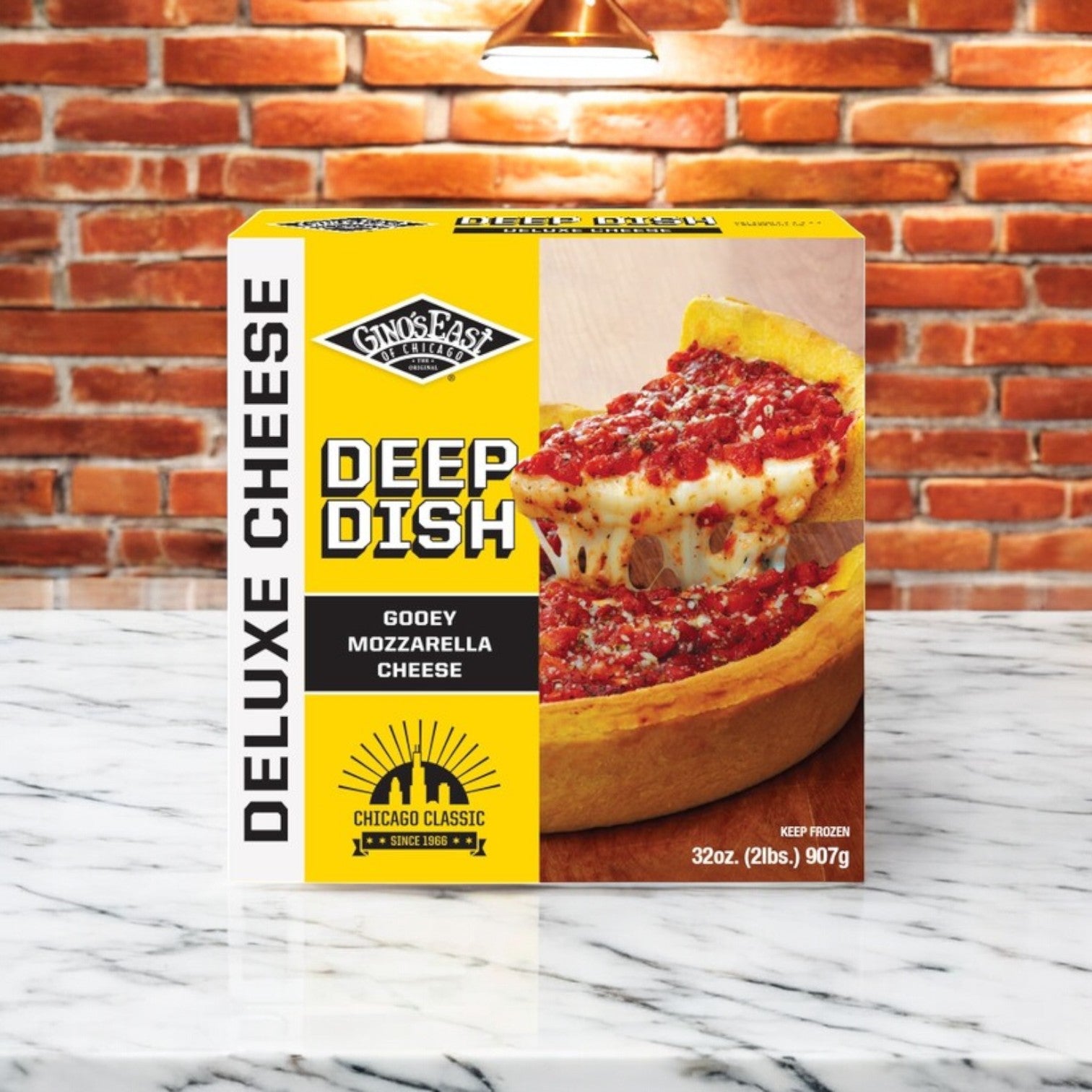 A box of Easy Lunches' "Chicago's Deep Dish Mix! 4 Total Deep Dish Chicago Pizza's" rests on a marble countertop, set against a brick wall background—ideal for anyone longing for the true taste of Chicago.