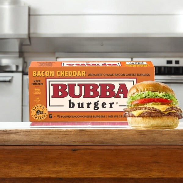 A box of Bubba Bacon Cheddar Cheese Burgers, 1 count, rests invitingly on the counter with a freshly made burger showcased upfront. The tantalizing aroma of USDA Choice beef fills the air as kitchen appliances quietly watch from afar.