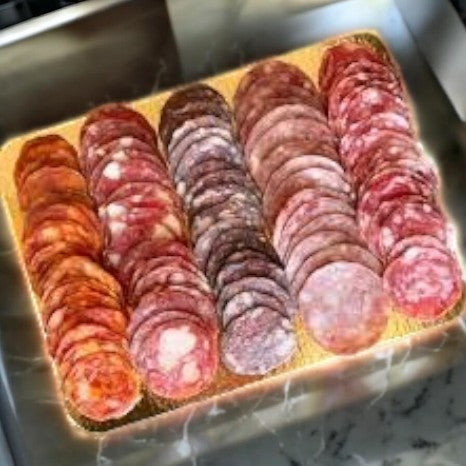 The Columbus Charcuterie Sampler-12 Oz-1 Count from Colombus elegantly adorns the counter, featuring a tray with five rows of sliced artisan meats such as salami and pepperoni.