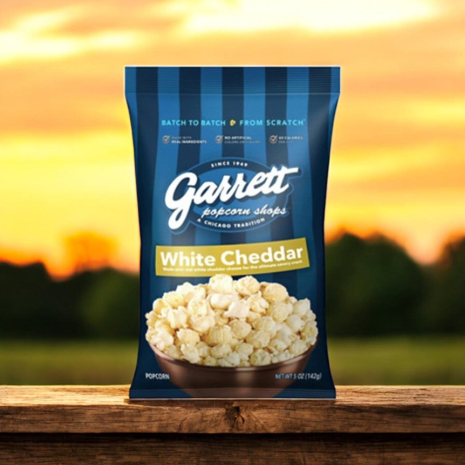 Garrett Popcorn White Cheddar – 5 oz Bag on a wooden surface with a blurred outdoor sunset background.