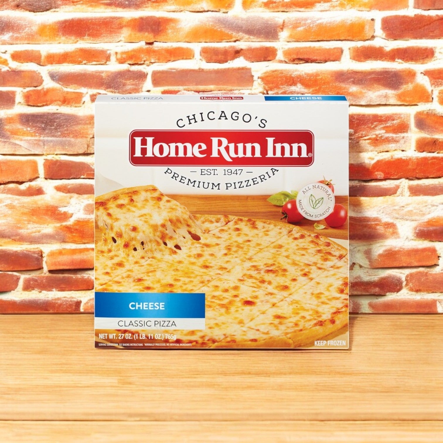 A box of Home Run Inn cheese classic pizza, from the Easy Lunches Eli's Cheesecake Celebration Sampler & Home Run Inn Pizza Combo, stands proudly against a brick background.