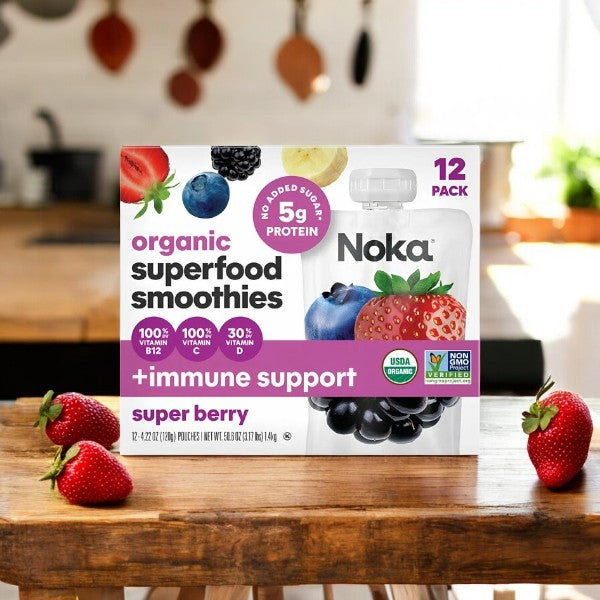 A box of 12-count Noka Organic Super Berry Smoothies is on a wooden table next to strawberries.