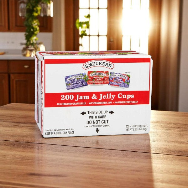 A case of Smucker's Assorted Jelly, 200 count with 0.5 oz packets, sits on a kitchen counter, displaying product images and handling info on the box. Each packet offers convenient, portion-controlled servings from the trusted Smucker's brand.