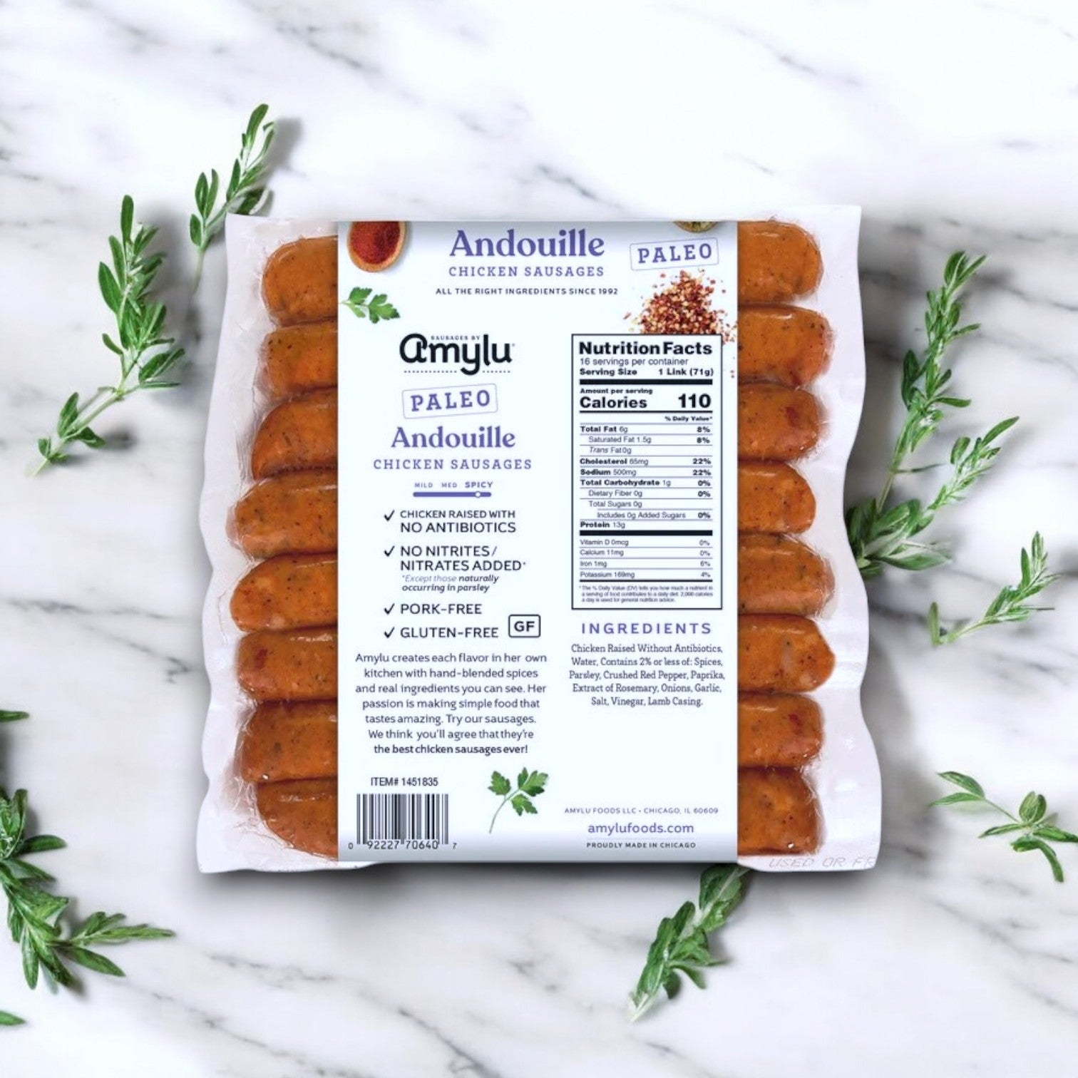 Amylu Paleo Andouille Sausage, 16 Count - 3 Packs, on a marble surface with herbs, showcases authentic flavor and highlights: paleo-friendly, no antibiotics, nitrites, nitrates, pork-free, and gluten-free.
