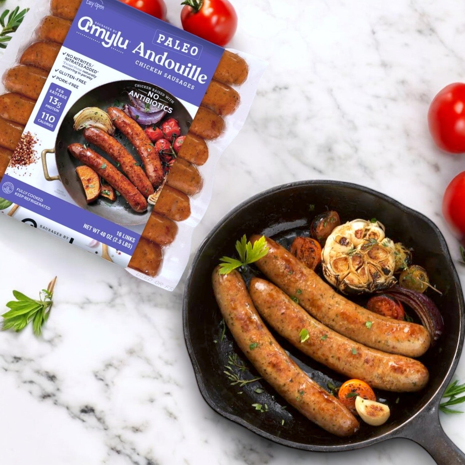 Amylu Paleo Andouille Sausages, 16 Count - 3 Packs, rest beside a skillet of cooked sausages, tomatoes, garlic, and herbs on marble, capturing authentic andouille flavor that's delicious and paleo-friendly.