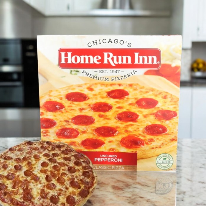 A 28 oz Home Run Inn Pepperoni Classic Pizza sits on the kitchen counter, flaunting its appealing packaging. The box promises a buttery flaky crust and 100% real mozzarella cheese, ensuring each bite is as delightful as it appears.