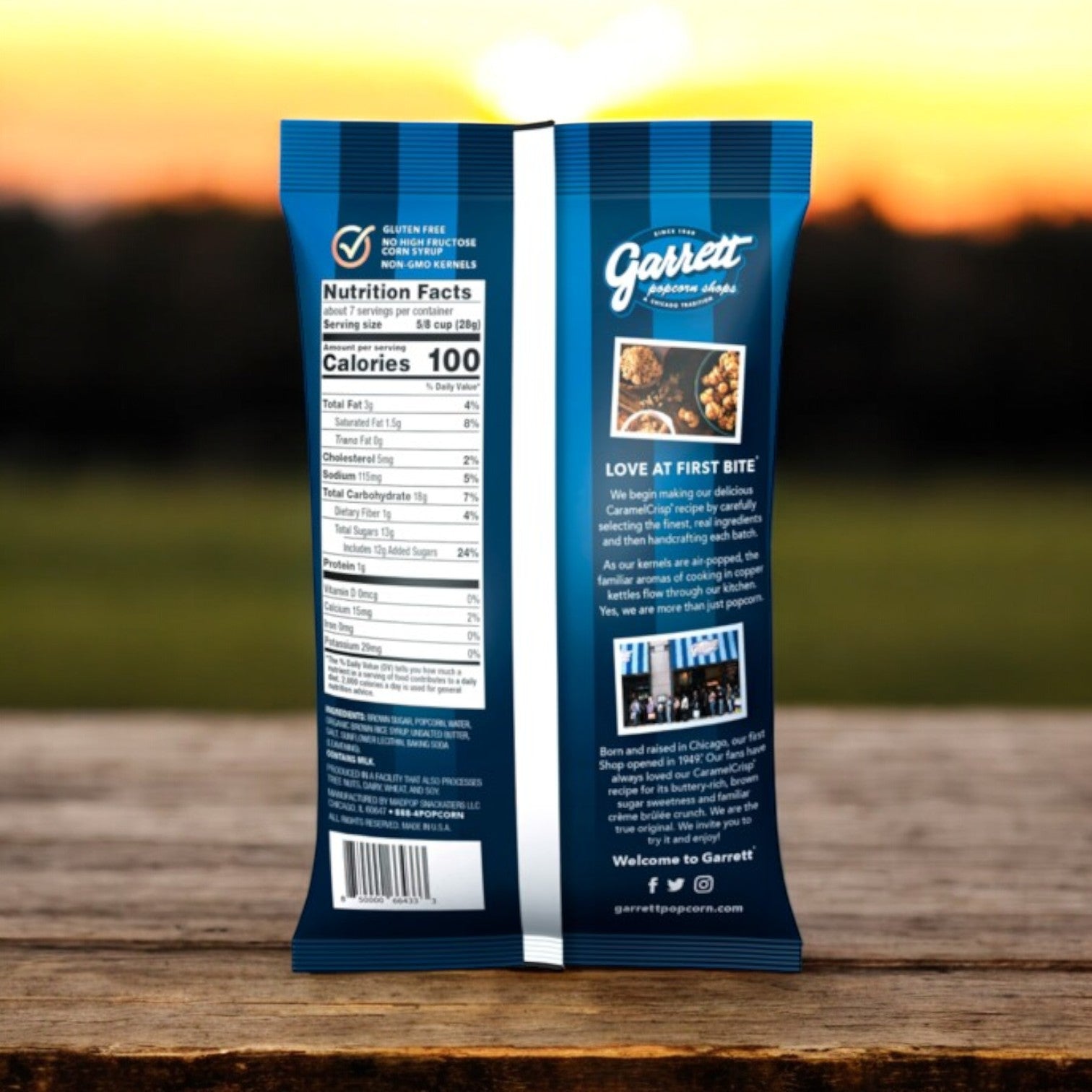The back of the Garrett Popcorn CaramelCrisp® 7.5 oz bag displays nutrition facts and a tempting description, with a blurred backdrop of trees and sky enhancing the snack's gourmet appeal.