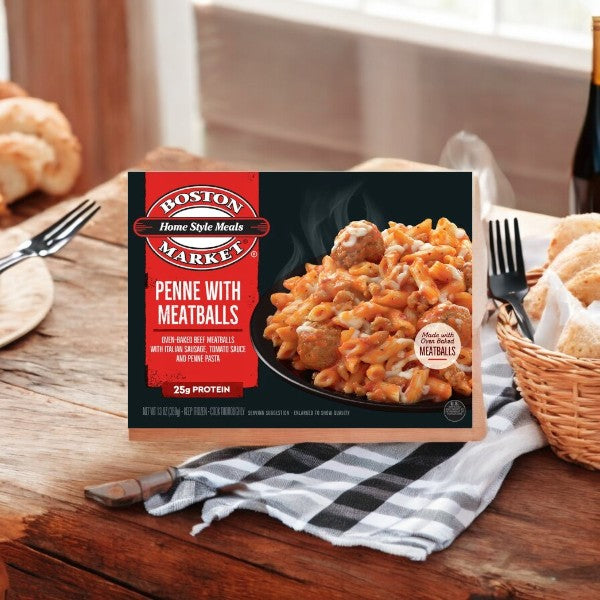 Boston Market Penne with Meatballs 13 oz by Smart Ones is showcased on a rustic wooden table, complete with a black and white checkered napkin and a bread basket in the background.