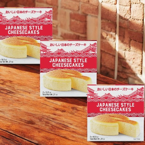 Three boxes of Kirkland Signature's Delcato Japanese Style Cheesecake sit on a wooden surface. Their red and white packaging showcases tempting images, each promising a light, fluffy texture and creamy interior that melts in your mouth.