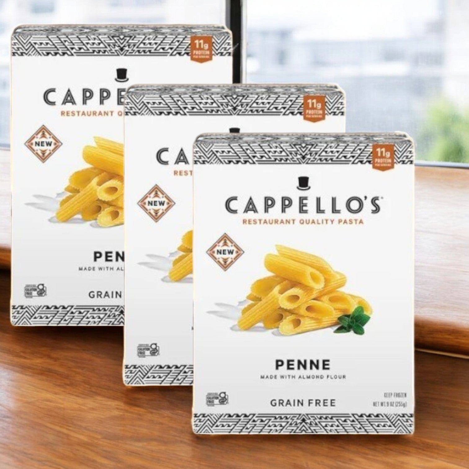 Three boxes of Cappello's Penne Pasta- 3 Count, made with almond flour, are shown on a wooden surface featuring gluten-free labeling and an 11g protein tag.