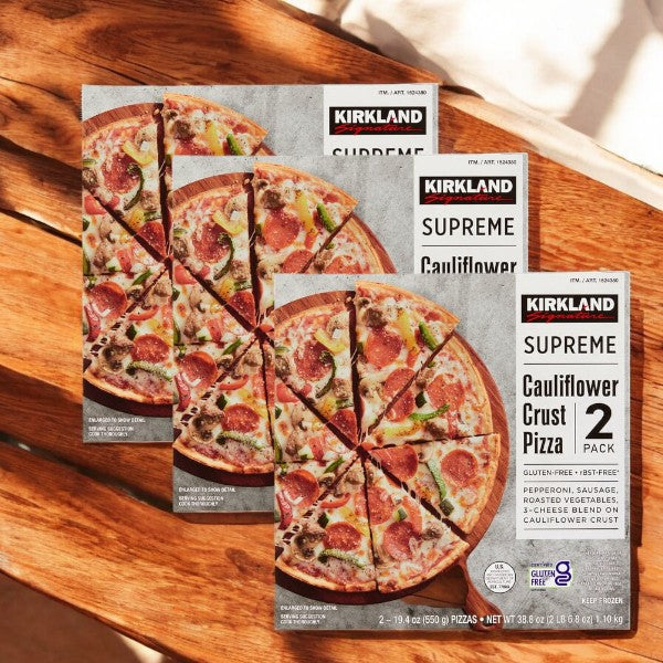 Kirkland Signature Cauliflower Crust Pizza, Supreme, 2-count - 3 Pack, featuring gluten-free pizza topped with pepperoni, sausage, and vegetables, is displayed on a wooden surface.
