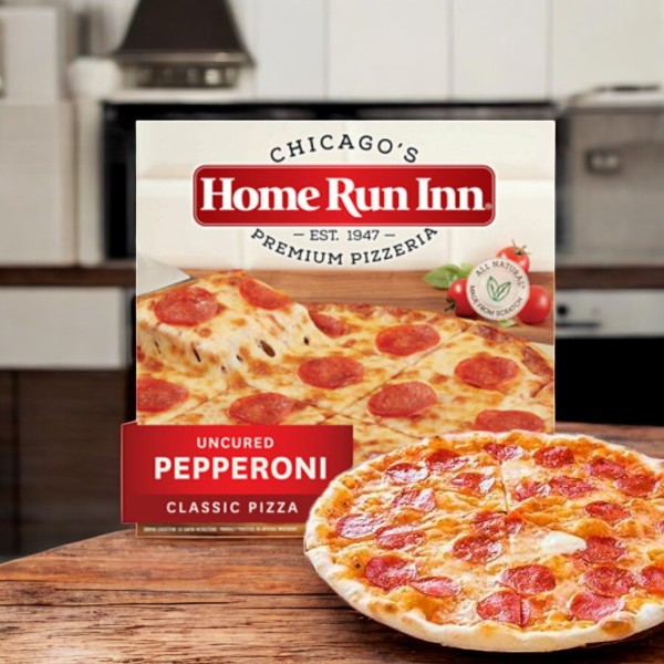 A Home Run Inn Classic Pizza, Uncured Pepperoni, 27 oz., sits in front of its box on a kitchen counter, both displaying the brand’s signature homemade-style pepperoni-topped crust.