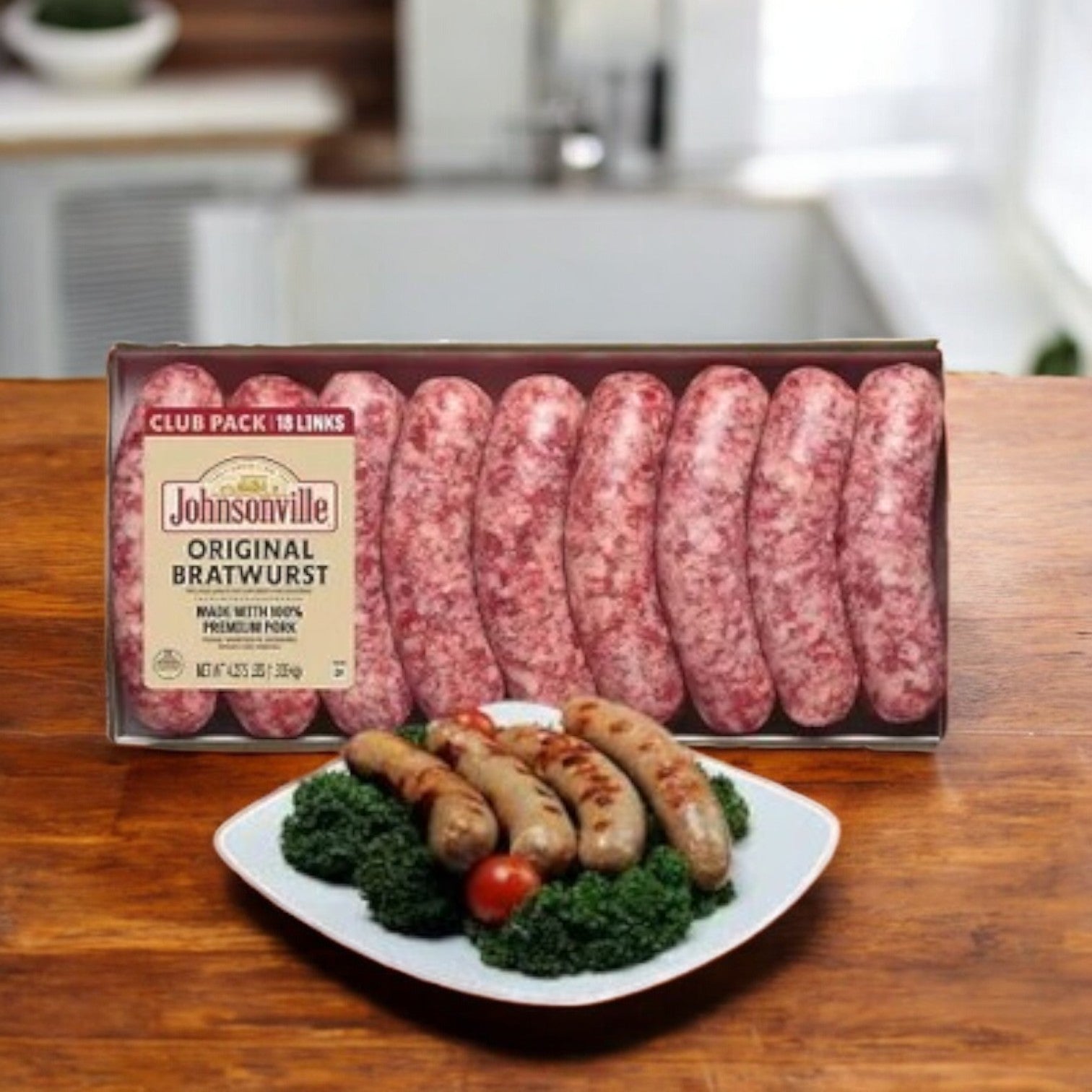 A package of Johnsonville Brats Original Pork Bratwurst Links-3 Cases sits behind a plate of grilled pork sausages with kale and tomatoes on a wooden table.