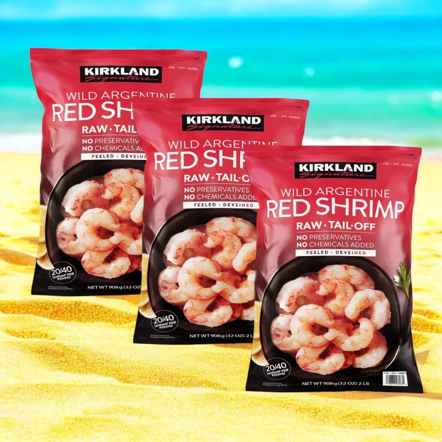 Three bags of Kirkland Signature Argentine Red Shrimp, 30-50-count, 2 lbs each (6 lbs total), are resting on a sandy beach with the blue ocean as a stunning backdrop.