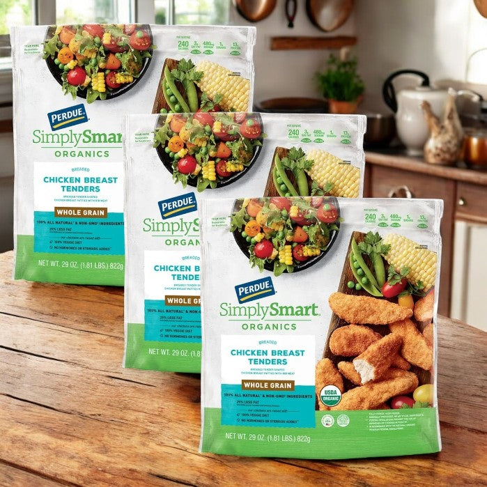 Three 22 oz bags of Perdue Breaded Gluten Free Chicken Breast Tenders sit on a wooden kitchen counter, with packaging featuring vibrant vegetables and corn, emphasizing the protein-rich 100% all-natural chicken.